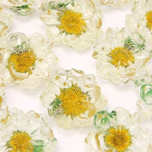 Macro shot of transparent daisy resin accessories with yellow centers and green leaves