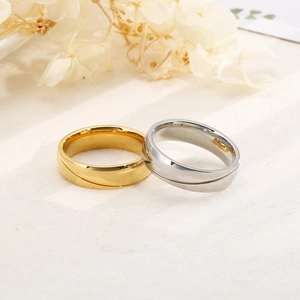 Close-up of gold and silver couple rings with diagonal grooves on textured linen fabric