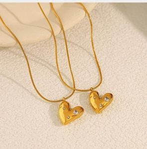 Detail of gold heart pendant with white rhinestones and delicate snake chain necklace