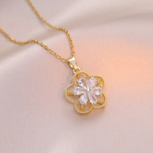 Macro shot of rotatable gold floral pendant with white petal gems on champagne silk