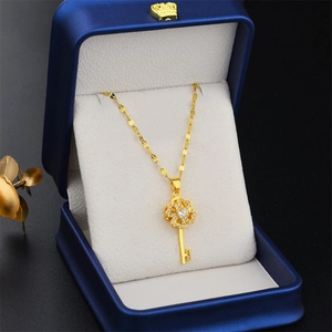 Rotating gold titanium key necklace with zircons in a navy blue velvet jewelry box