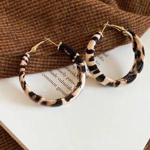 Detailed view of beige leopard print large hoop earrings on elegant aesthetic background