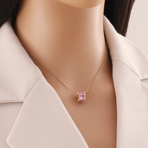 Close-up of a pink square zircon pendant on a gold stainless steel chain worn by a model