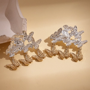 Détail de boucles d'oreilles papillon bicolores avec glands sur fond en pierre
