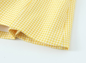 Detailaufnahme von gelb-weißem Plaid-Seersucker-Stoff und hochwertigen Nähten am Saum