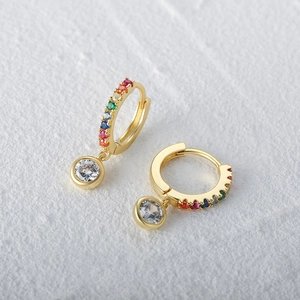 Macro shot of gold hoop earrings with rainbow zircon stones and a clear round pendant