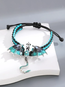 Macro-opname van geweven drakenarmband met blauwe gradiëntvleugels op steen