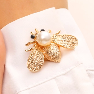 Gros plan détaillé d'une pince à chemise abeille dorée avec perle et ailes texturées