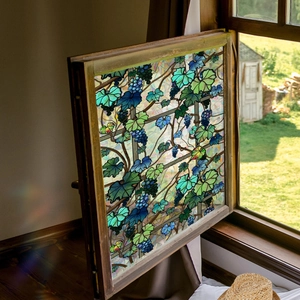 Close-up of decorative grapevine stained glass window film in a rustic wooden frame