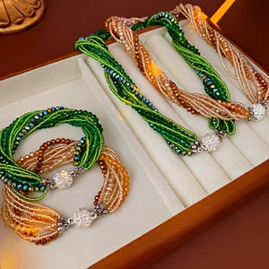 Détail macro de perles de cristal émeraude et ambre avec un fermoir magnétique pavé de cristaux