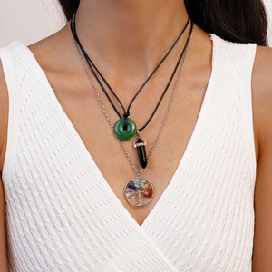 Détail du collier superposé avec pierre en résine verte et pendentif arbre de vie