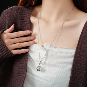 Detailed view of a silver titanium steel ball pendant necklace on a model's neck