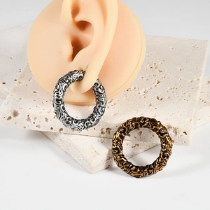 Detail of vintage embossed hoop earrings in silver and gold on a silicone ear model