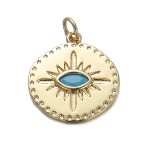 Macro view of a gold-plated circular pendant with a blue evil eye and radiant details