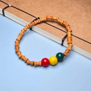 Close-up of bamboo-shaped sandalwood beads with colorful resin accents on a notebook