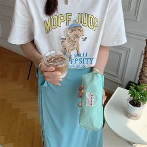 Close-up of mint green macaron storage pouch held by model in a bright home setting