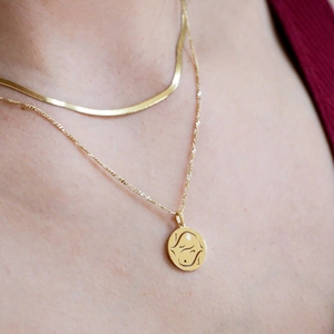 Layered gold stainless steel necklaces with zodiac pendant and sleek snake chain on model