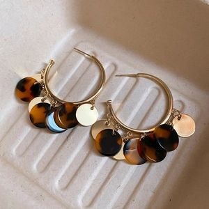 Detail of vintage leopard print resin discs and gold metal hoops on a textured tray