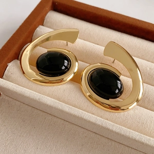 Detailed close-up of vintage gold spiral earrings with black oval gems in a velvet box