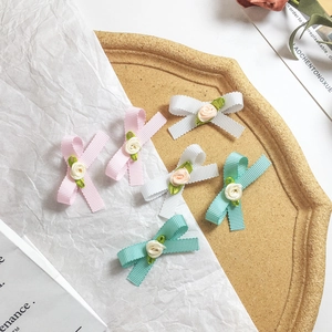 Détail de pinces à cheveux en ruban avec roses en satin rose, blanc et menthe
