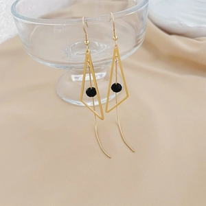 Detail of long gold geometric triangle earrings with black beads and fine chain tassels