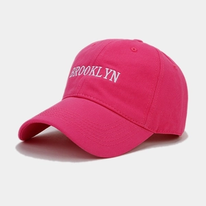 Close-up of white Brooklyn embroidery on rose red cotton twill baseball cap