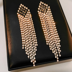 Macro shot of luxury long fringe earrings with black rhinestones on leather background