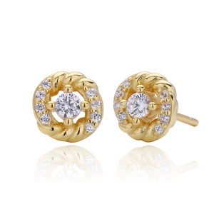 Macro shot of gold twist earrings with white zircon stones and mirrored reflection