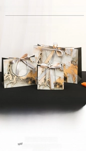Close-up of gold leaf detailing on marble gift bags with elegant ribbon handles