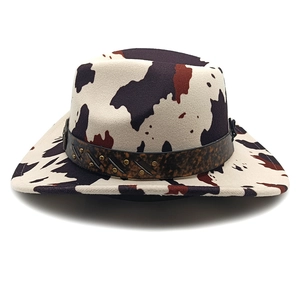 Detailed view of the cow print cowboy hat featuring leopard band and metal rivets