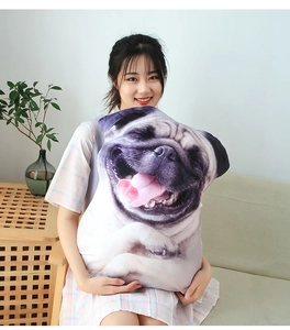 Detail shot of a soft plush pug dog throw pillow held by a model in a cozy home setting