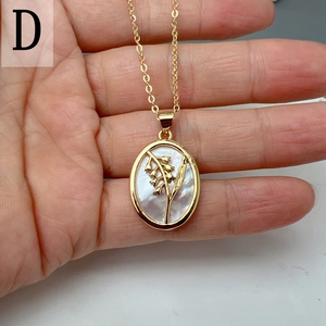 Detail of oval mother of pearl shell pendant with golden floral lily of the valley motif