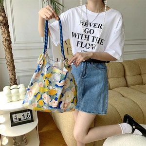Floral canvas tote bag with knitted handles shown in a cozy indoor lifestyle setting