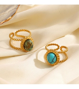 Detail of gold-plated rings with turquoise and brown stones on beige silk fabric