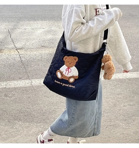 Detail of black quilted tote bag with brown bear embroidery and matching bear charm