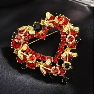 Macro shot of a red heart-shaped brooch with sparkling rhinestones on black silk