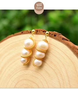 Detail of natural pearls wrapped in gold wire hanging on a rustic wooden stump