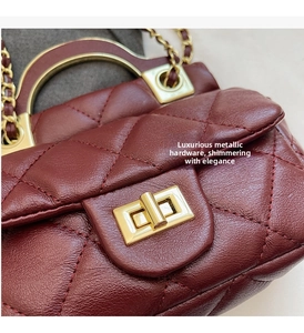 Detailed close-up of burgundy quilted leather with gold chain and turn-lock closure