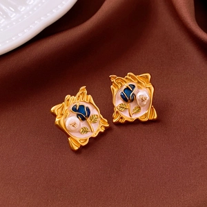 Detail of vintage enamel earrings with pink base, blue rose, and white pearl inlay