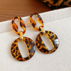 Close-up of tortoise shell resin hoop earrings with elegant golden metal links