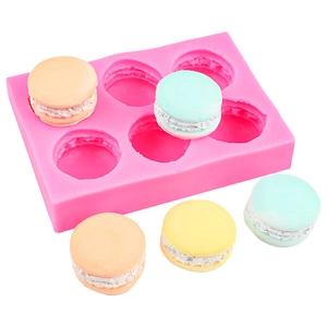 Pink 6-cavity silicone macaron mold with colorful finished dessert samples on white background