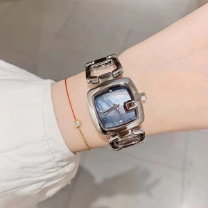 Detail of silver square watch with blue mother-of-pearl dial on woman wrist