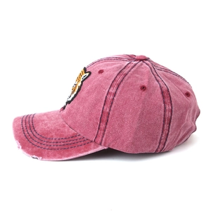 Macro shot of tiger embroidery on vintage distressed burgundy denim baseball cap