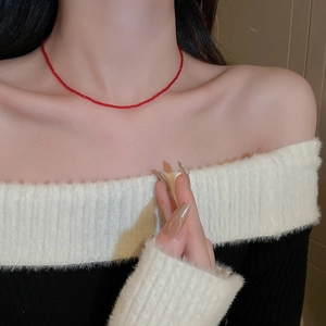 Close-up of minimalist tiny red beads necklace worn by model on collarbone