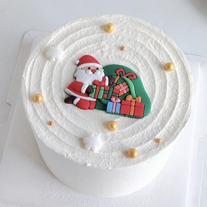 Weihnachtskuchendeko mit Weihnachtsmann und Goldperlen auf weißem Zuckerguss
