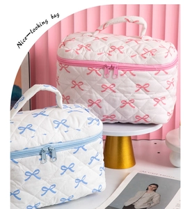 Detail of quilted cosmetic bags with bow prints, reinforced handles and dual zippers