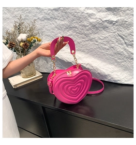 Detail der rosaroten herzförmigen Tasche mit 3D-Nähten, Goldreißverschlüssen und Kette