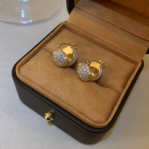 Detailed macro view of mermaid pearl and zircon hoop earrings in a velvet jewelry box