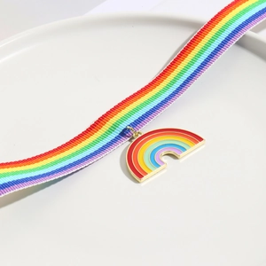 Detail of colorful rainbow ribbon strap and heart-shaped enamel pendant on white plate