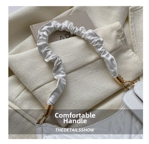 Close-up of white quilted leather bag featuring a gold hardware and scrunchie handle detail